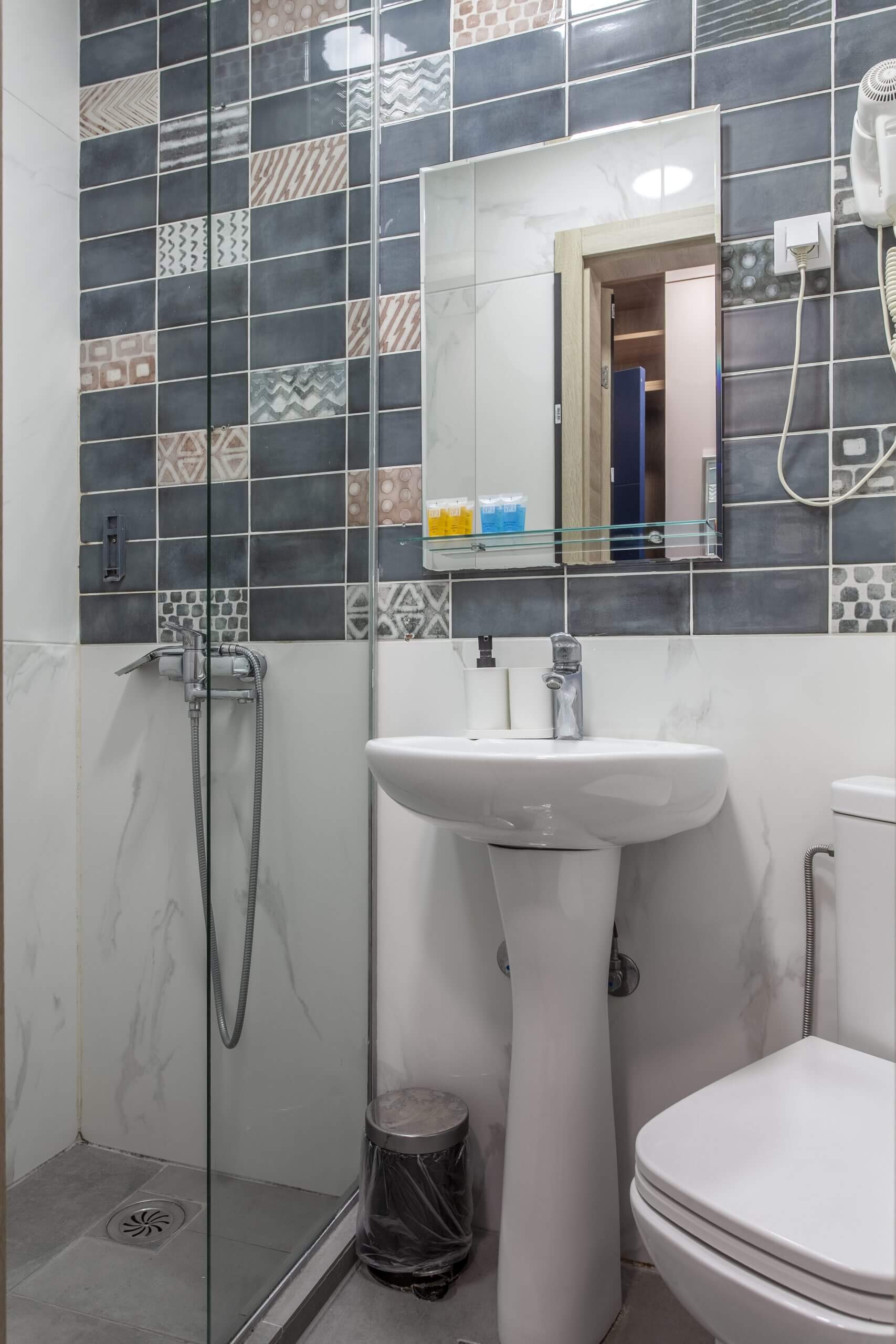 Fotografija prikazuje moderno kupatilo sa tuš kabinom, lavaboom